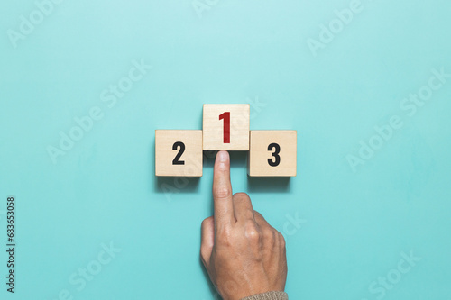 A man pushing wooden cube with the number one for task priority and management. Set work priority, arrange to do list. Concept of success,winner, victory or top ranking