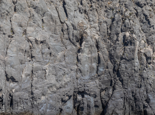 Weathered seaside rock face texture . Aged volcanic stone wall surface background pattern with cracks and scratches. Ischia Island, Italy.