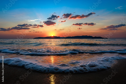 Picture of the beach at sunset with the foreground being a sandy beach and sea water. The background is Khram Yai Island. The name of the beach is Haad So, Chonburi Province, Sattahip District.