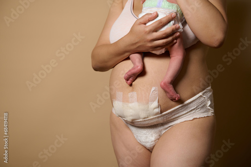 Cropped view of woman mother standing together with her newborn baby. Real body of women after few days of childbirth.