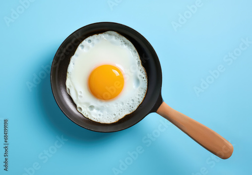 A fried egg in a frying pan on a blue background