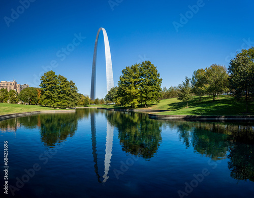 View across blue lake in the National Gateway Park to Gateway Arch in St Louis Missouri with reflection in the calm water