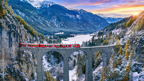 Aerial view of Train passing through famous mountain in Filisur, Switzerland. Landwasser Viaduct world heritage with train express in Swiss Alps snow winter scenery.