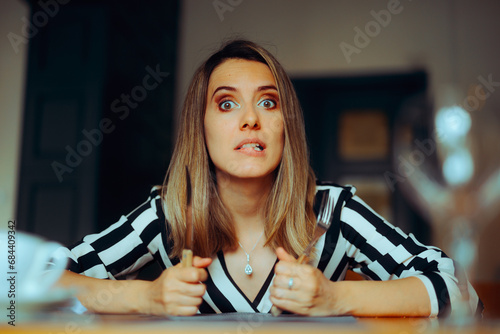 Hungry Woman Holding a Fork and a Knife Waiting her Meal. Funny lady impatient with her dinner starving and craving 