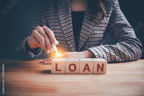 Businesswoman in checkered suit with wooden blocks cubes text "LOAN". Loan payment car and house, Interest and fees from loans are main revenue for banks, Business and finance concept.
