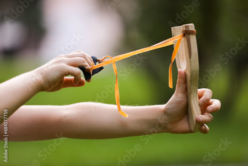 Little girl playing with slingshot outdoors, closeup