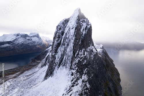 Aerial drone photo of snowy mountain hike up Segla in Senja, Norway. Snowcapped mountains in the Arctic Circle of Northern Norway. Famous hike on Senja island. Shot in October.