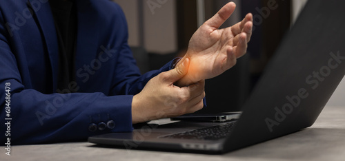 close up businessman massage on hand palm while feel stiffness after hard working to relief pain or cramp or carpal tunnel for office syndrome and health lifestyle concept