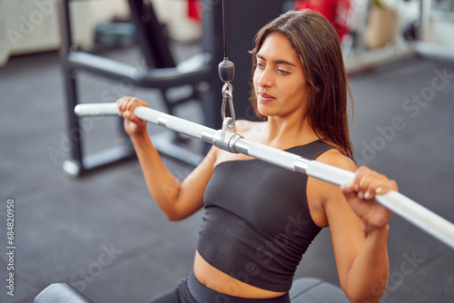 high angle view of latin woman doing wide grip lat pulldown in the gym