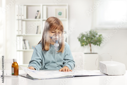 Little girl reading a book and using a nebulizer