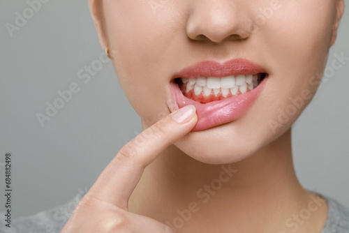 Woman showing inflamed gum on grey background, closeup