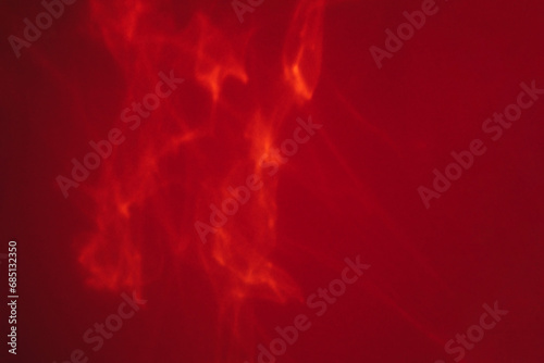 Abstract blurred red background, backdrop with sun reflection. Caustic effect of sunlight. Empty space for design with solar glare