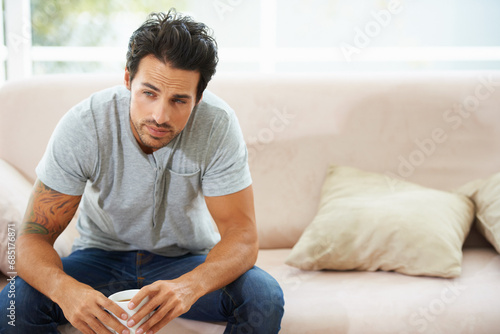 Depression, thinking and sad man on a sofa with stress, anxiety or broken heart at home. Fail, crisis or male person in living room overthinking, disaster or lonely, worried or disappointed in house