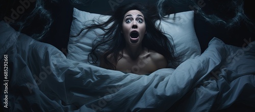 Startled woman arising from a bad dream in her nighttime slumber copy space image