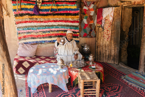 Man in traditional clothes preparing Moroccan tea in cup