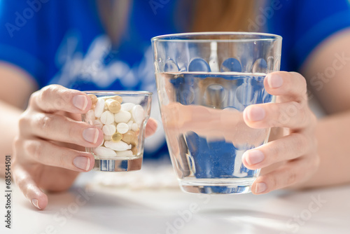 Kobieta popija lekarstwa pełną szklanka wody