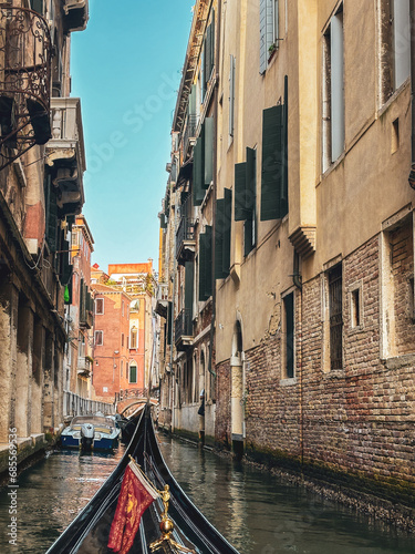 Gondola moving between houses in narrow canals within the city of Venice, Italy