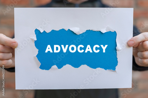 Man holding white and blue sheets of paper with word: ADVOCACY. Business advocacy and lawyer consulting concept. Advocacy legal service.