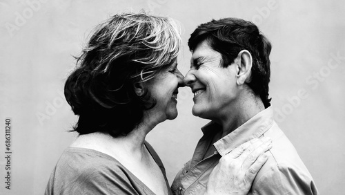 Senior gay lesbian couple kissing outside. LGBTQ aged lovers having tender moment. Black and white editing