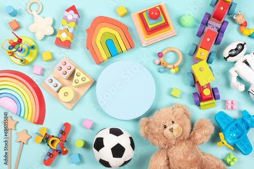 Empty round platform podium stand, with teddy bear, robot and many natural wooden ecological sustainable educational children toys. Baby kid toys on light blue background. Top view, flat lay