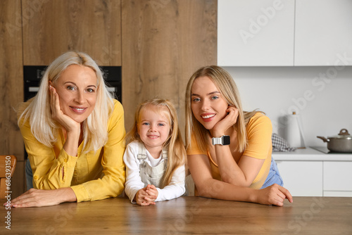 Cute little girl with her mother and granny in kitchen