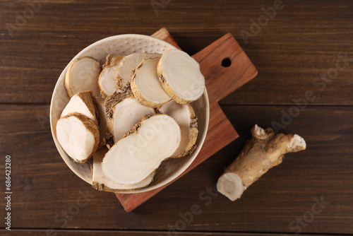 Cut horseradish roots on wooden table, flat lay