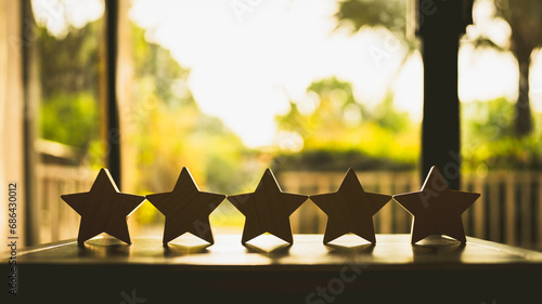 Businessman hand picking up model star on wooden table, Five star shape. The best excellent business services rating customer experience concept.