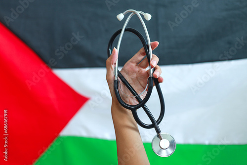 Hand holding stethoscope with Palestine flag on the background