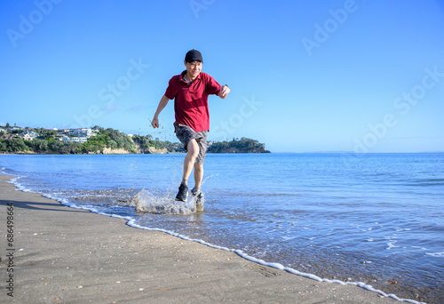 Man running in water on Milford Beach. Auckland.