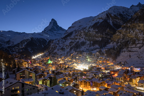 Panoramic landscape of Zermatt city Valley famous travel ski resort and iconic Matterhorn peak at dawn in the swiss alps, Switzerland. The snow covered village and church in Canton Valais in winter.