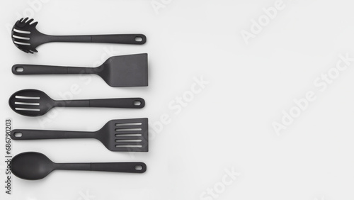 Group of vertically aligned spoons and spatulas, isolated on grey copy-space background.