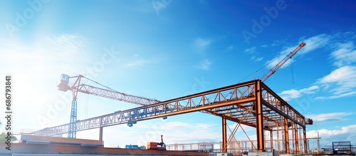 Installing a steel roof truss frame using a mobile crane indoors beneath a blue sky in a factory during construction Copy space image Place for adding text or design