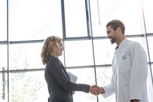 Businesswoman and doctor shaking hands in hospital