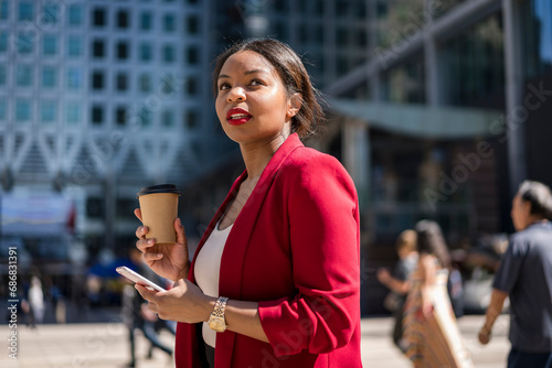 Portrait of businesswoman with coffee to go and cell phone, London, UK