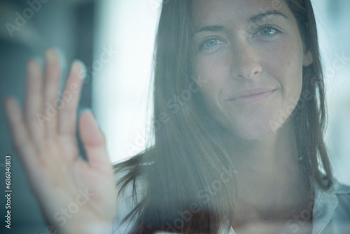 Portrait of smiling young woman behind windowpane