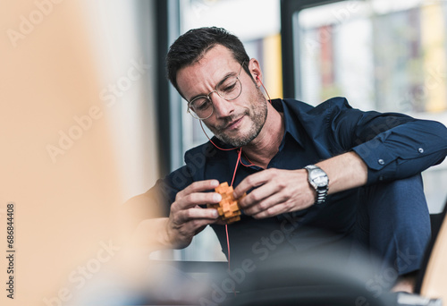 Mature man sitting in office assembling wooden cube puzzle