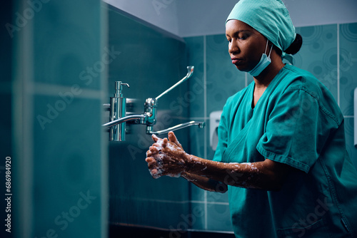 Black surgeon washing her hands before operation at clinic.