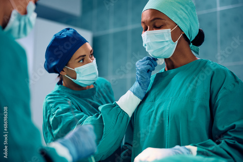 Black female doctor sweating during complicated surgery in operating room.