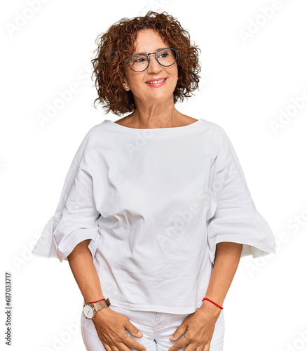 Beautiful middle age mature woman wearing casual clothes and glasses looking away to side with smile on face, natural expression. laughing confident.