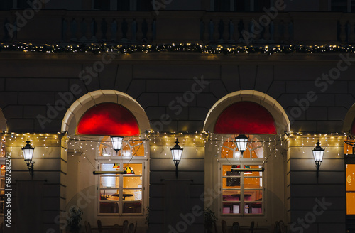 Old sconces glow with a warm light over the windows. ?enter of Lviv at night in the area of the town hall. The concept of the evening city, Christmas and New Year in the historical part of the city.