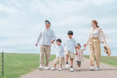 青空の公園を歩く家族・ファミリー・夫婦と子供 