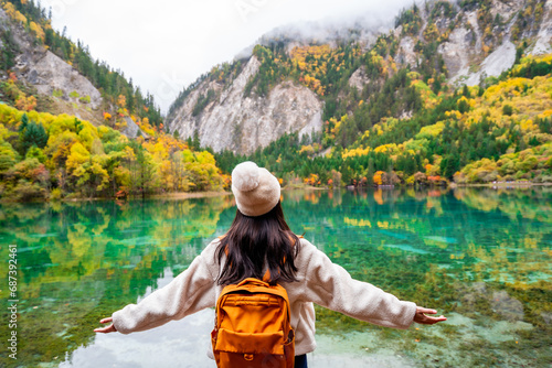 Young female tourist looking at beautiful autumn scenery landscape at jiuzhaigou national park in Sichuan, China