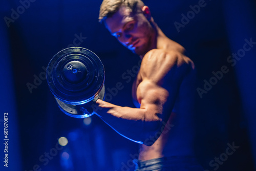 A Strong, Shirtless Man Gripping a Heavy Dumbbell with Determination and Strength. A man with no shirt holding a dumb bar