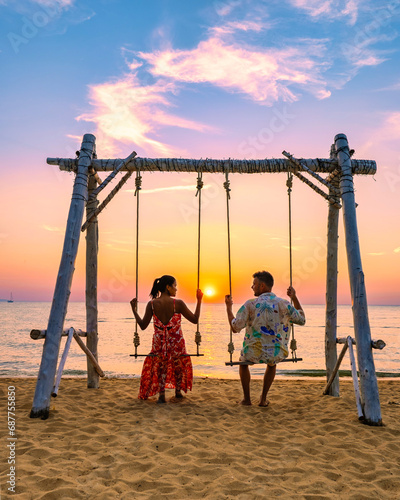 Najomtien Beach Pattaya Thailand, a couple man and a woman mid age watching the sunset on the beach on a swing