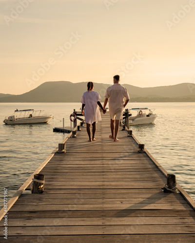 A couple at a wooden pier in the ocean during sunset in Samaesan Thailand