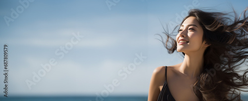 リゾート旅やヨガを連想させる日焼けや紫外線も厭わない海で太陽光を浴びるヘルシーな女性イメージ_コピースペースあり