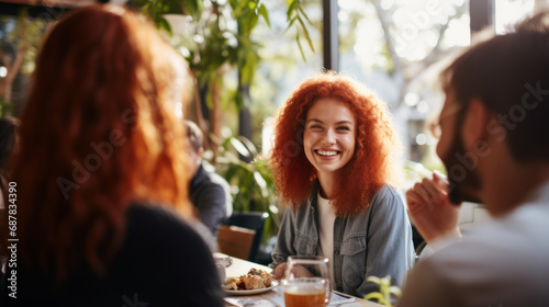 Redhead ginger caucasian business woman having a friendly lunch with colleagues at a local cafe, she engages in casual conversation, fostering a positive and collaborative atmosphere