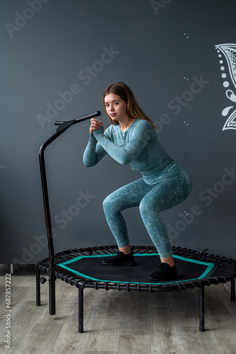  fitness woman in sportswear doing exercises on a sports trampoline in the gym near the wall.