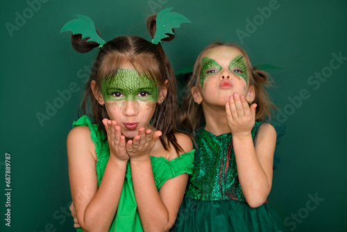 Beautiful girls with makeup in the guise of a green dragon are blowing kisses while waiting for the new year