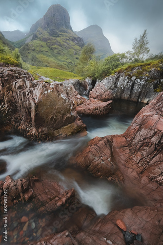 Moody, atmospheric mountain landscape along the River Coe to the Three Sisters of Glencoe in the Scottish Highlands, Scotland.